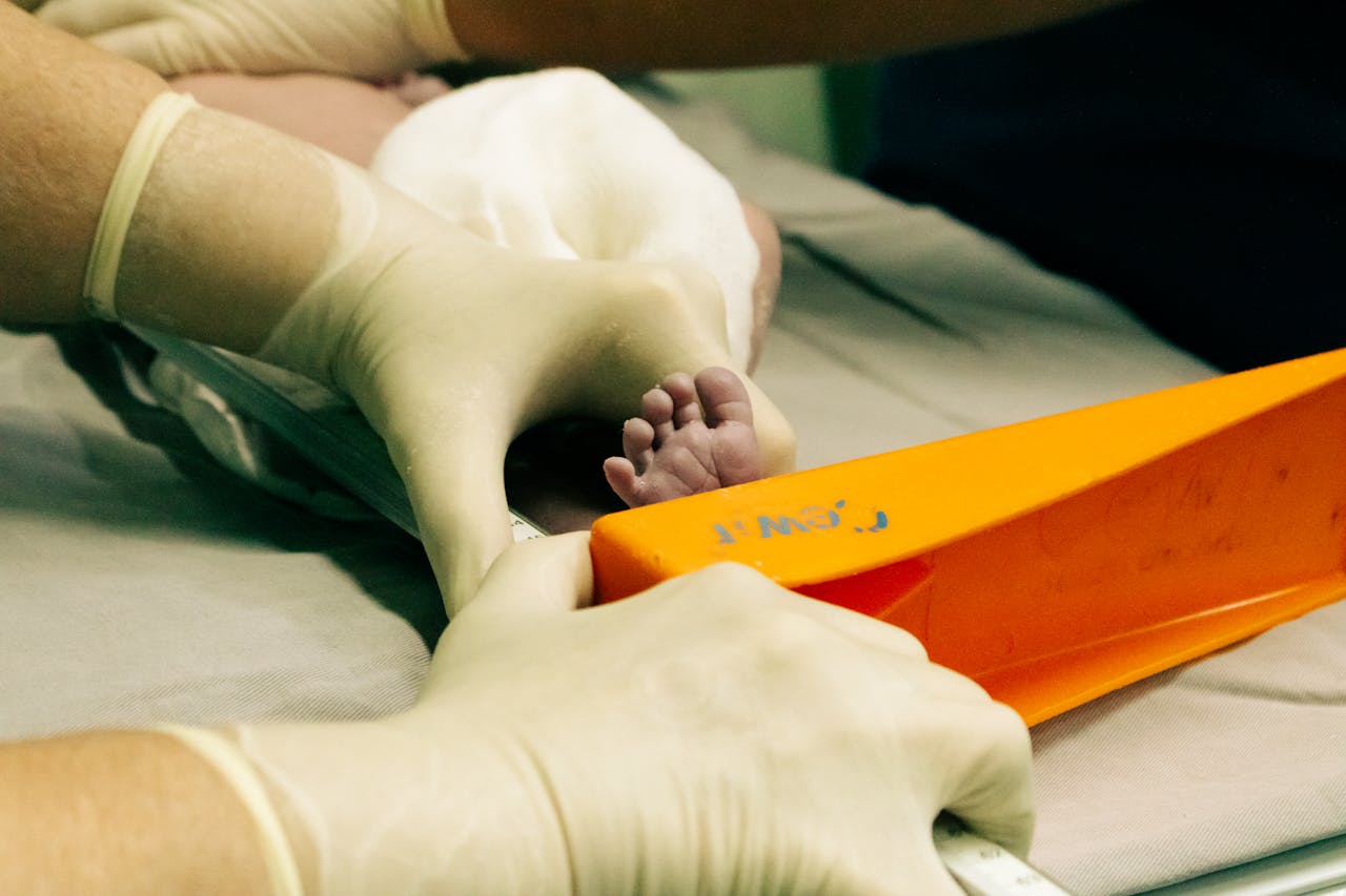 Newborns foot being measured by a nurse in medical setting with care.